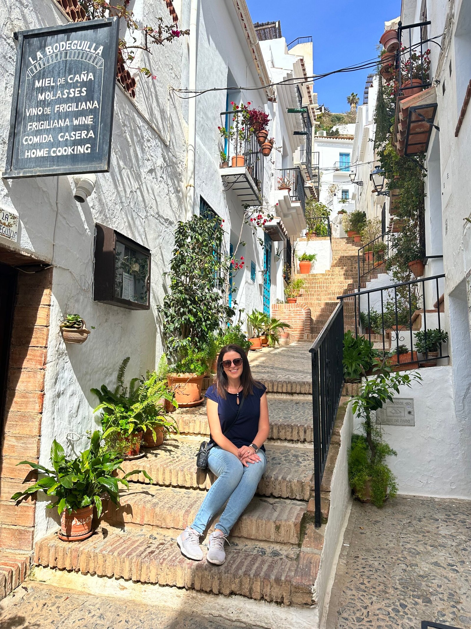 Jessica sitting on the steps of in a white washed Spanish town.