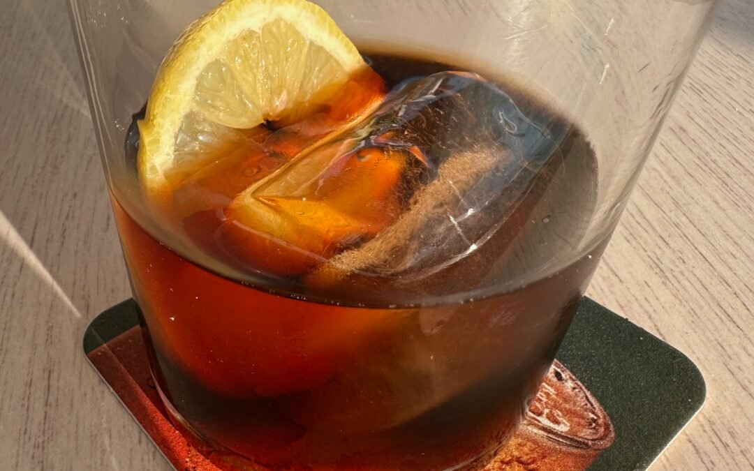 A glass of Spanish vermouth with orange peel on ice