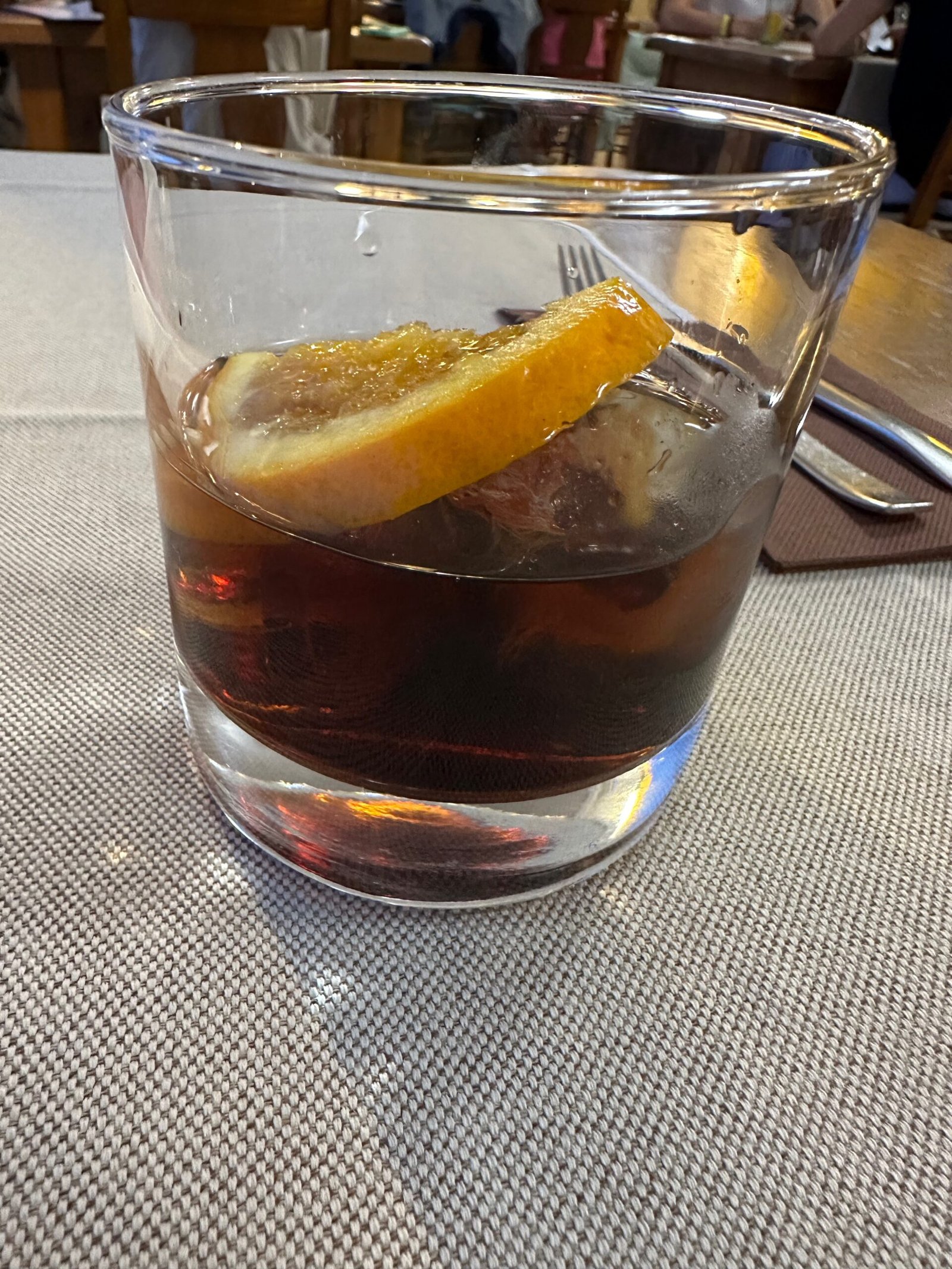 A glass of Spanish vermouth with orange peel on ice